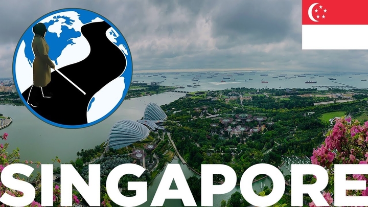 An image of Singapore from an ariel view. In the top left corner is the PTC Logo. A cartoon Mona with her cane walking across a street on a globe. IN the top right is the flag of Singapore.  