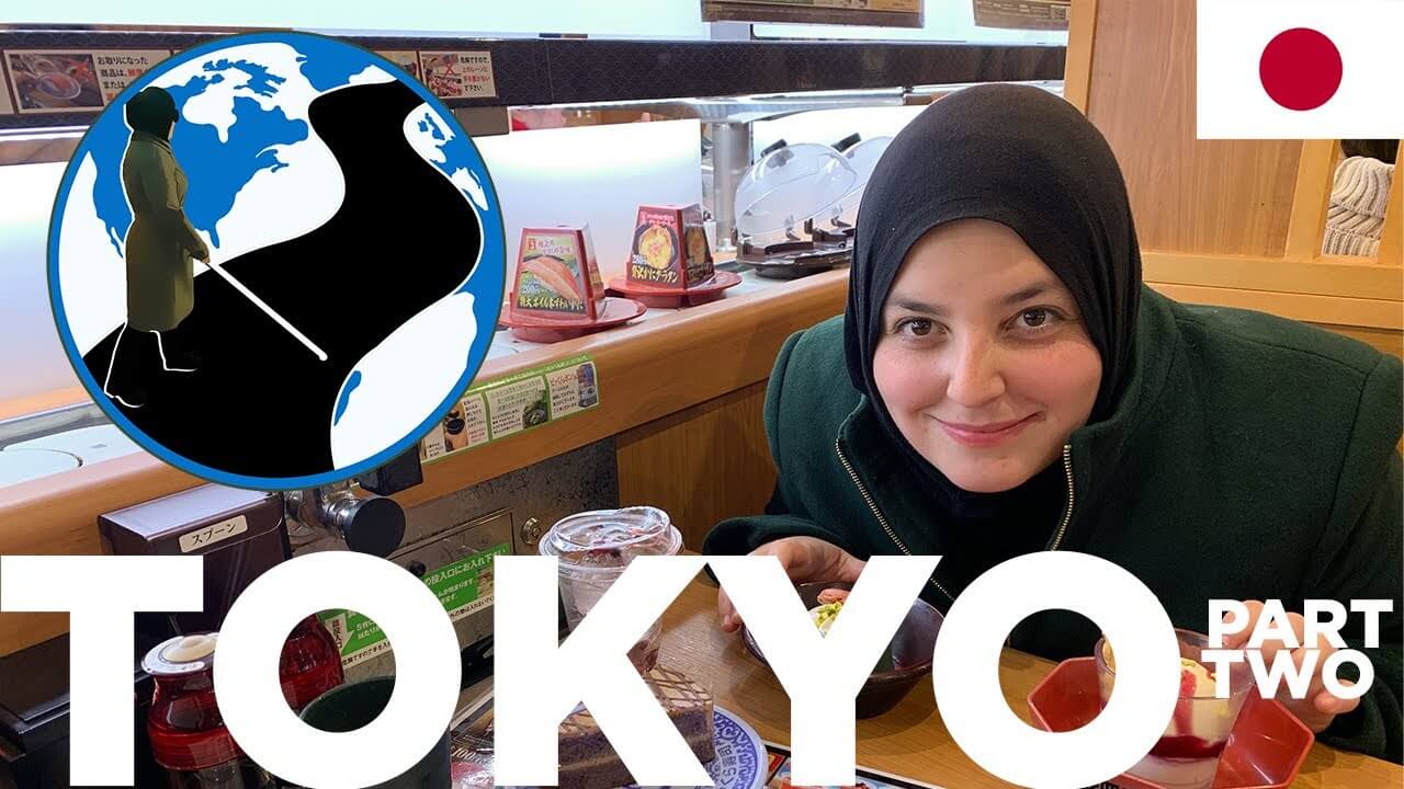 An image of Mona smiling at a table in a Japanese restaurant. A conveyor belt with food next to her. In the top left corner is the PTC Logo. A cartoon Mona with her cane walking across a street on a globe. In the top right the flag of japan.